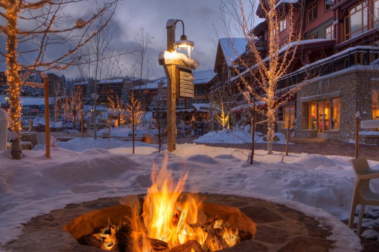 A cozy fire pit glowing warmly in the snow at night, surrounded by a serene winter landscape.