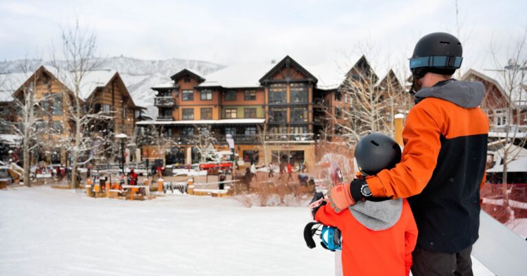 A man and a child stand together on a snowy slope, enjoying a winter day outdoors.