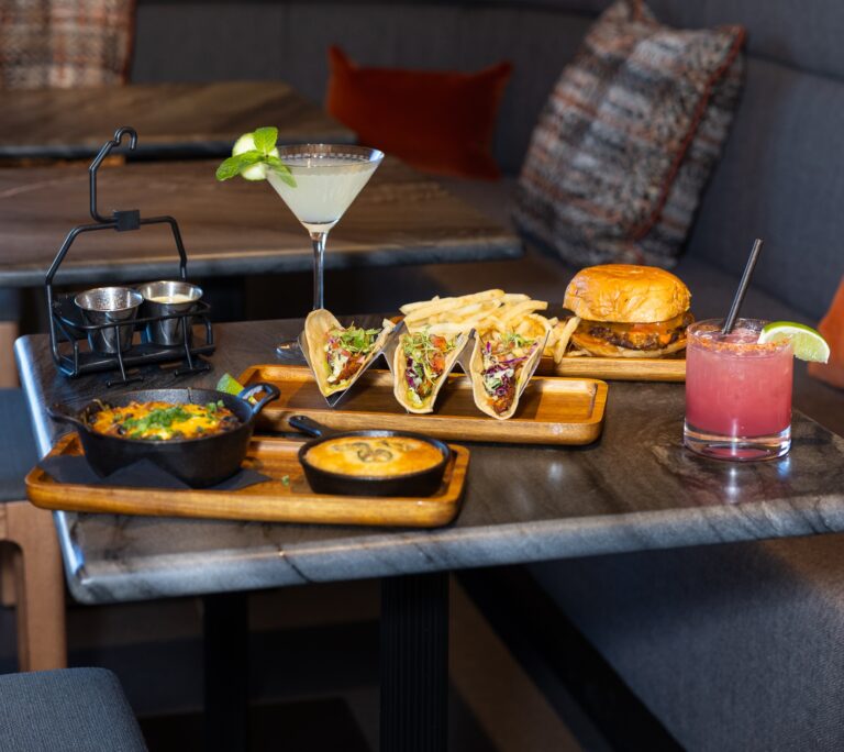 A colorful table set with an assortment of delicious food and refreshing drinks, inviting guests to enjoy a meal together.
