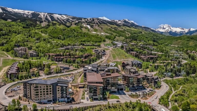 Scenic aerial shot of Aspen, Colorado, highlighting the town's picturesque streets and stunning mountain backdrop.