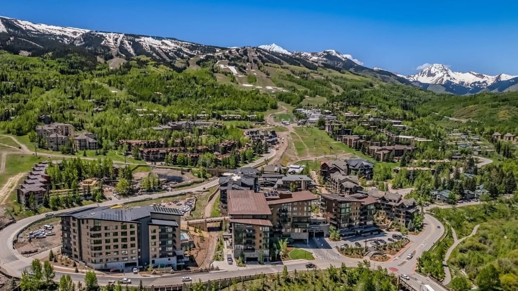 Scenic aerial shot of Aspen, Colorado, highlighting the town's picturesque streets and stunning mountain backdrop.